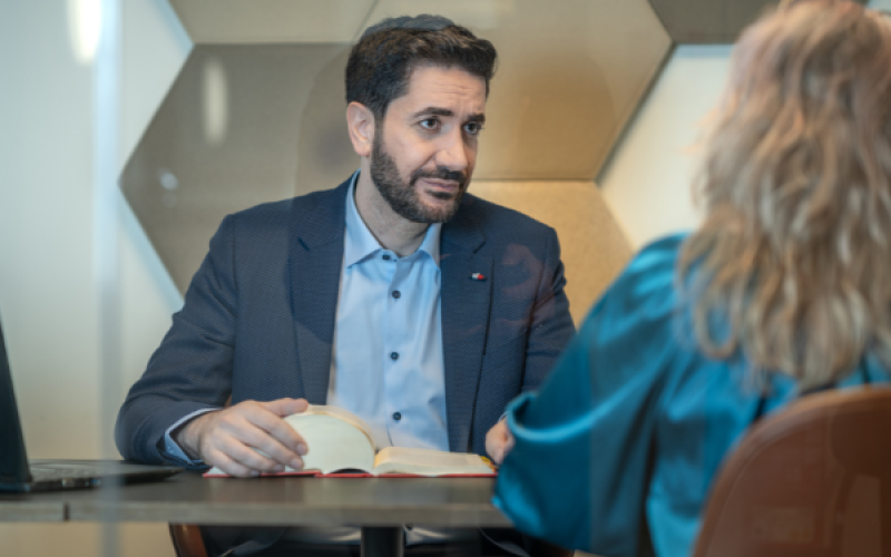 Herr Aksöz mit einer Person am Tisch, im Gespräch.